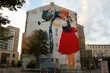 Dziewczynka podlewa drzewo konewką. Oryginalny mural w centrum
