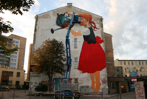 Dziewczynka podlewa drzewo konewką. Oryginalny mural w centrum